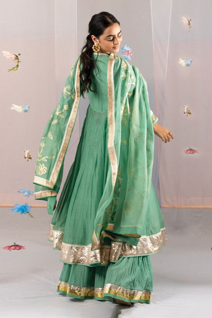 Laurel green anarkali with gota, lace embroidered sleeve hem. Paired with gota bordered sharara and dupatta.
Components: 3
Pattern: Embroidery
Type Of Work: Gota, lace
Neckline: V neck
Sleeve Type: Full sleeves
Fabric: Chanderi
Color: Green
Other Details: 
Side tassel detailing
Gota embroidery on sharara hem
Occasion: Puja - Aza Fashions V Neck Anarkali, Chanderi Anarkali, Gota Embroidery, Green Anarkali, Laurel Green, Sharara Set, Lace Neckline, Pattern Embroidery, Fashion App