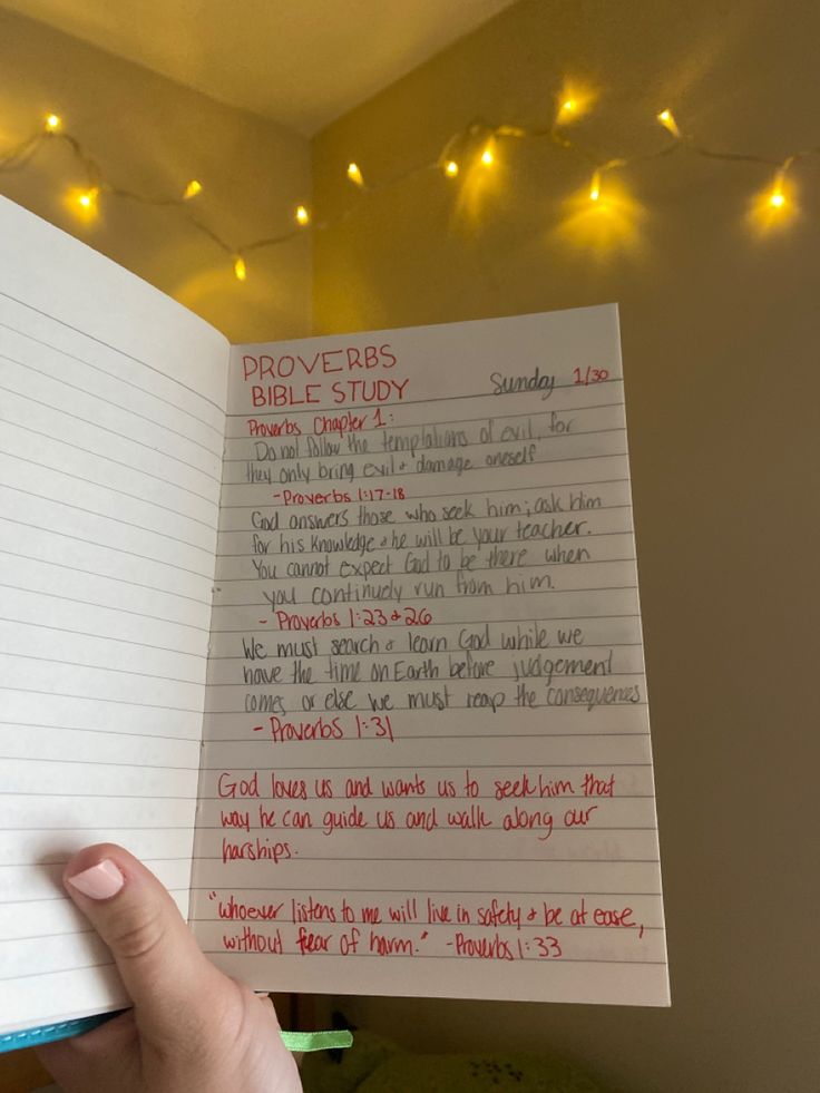 a hand holding up a notepad with writing on it and lights in the background