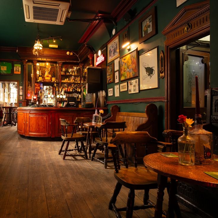 the interior of a bar with wooden tables and stools in front of green walls