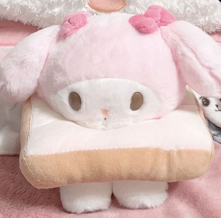 a stuffed animal that looks like a bunny is next to a small white dog on a pink blanket