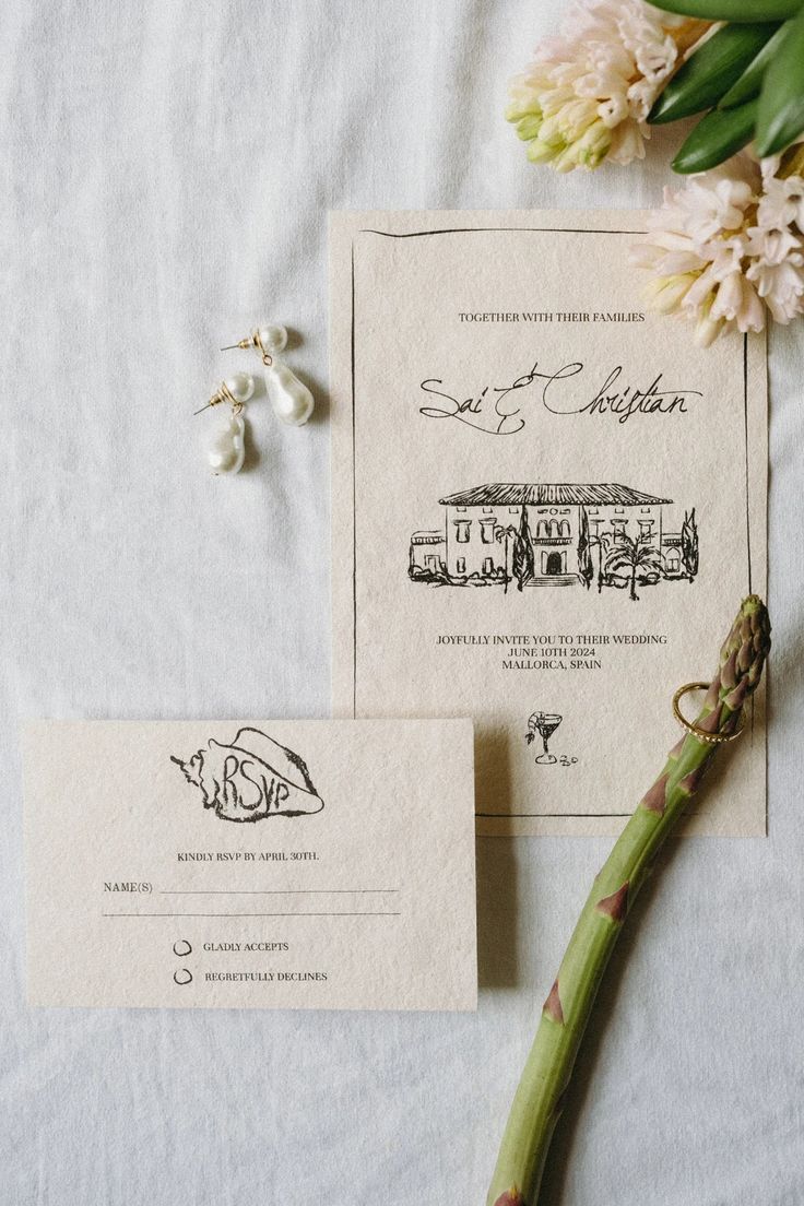 the wedding stationery is laid out on top of the bed with flowers and pearls