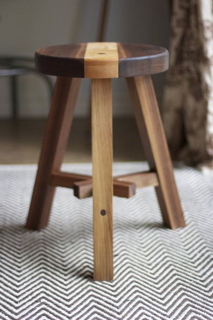 a wooden stool sitting on top of a rug