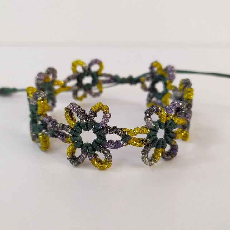 a close up of a bracelet made out of beads and string with flowers on it