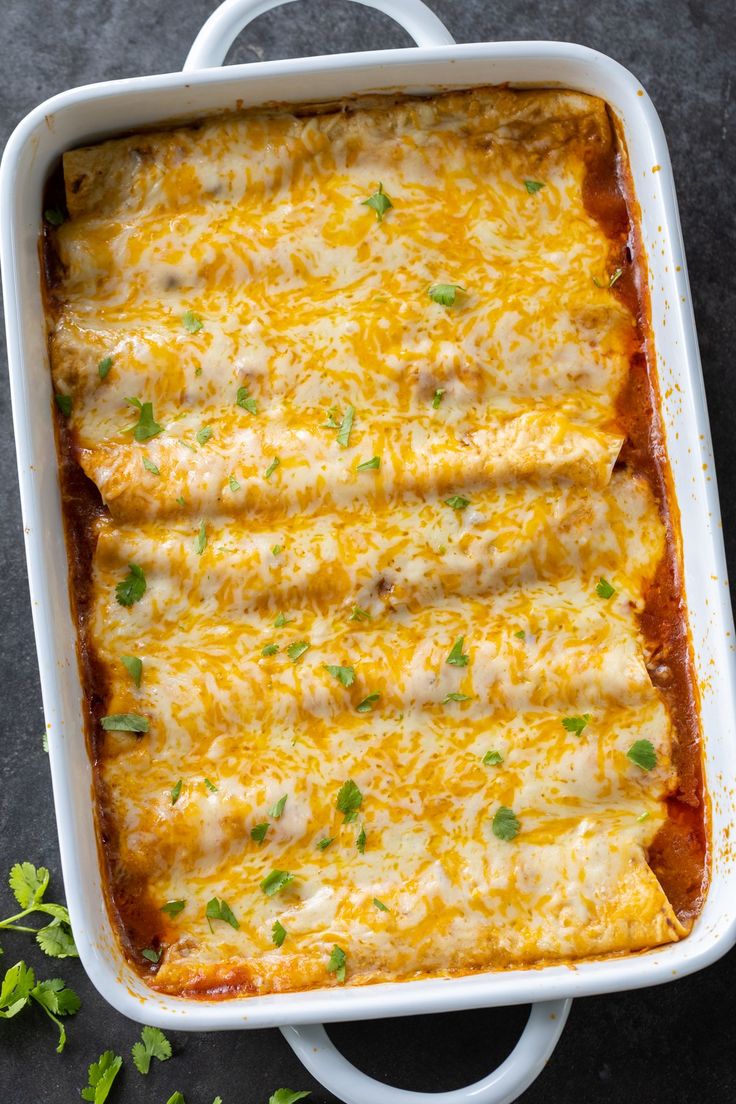 an enchilada casserole in a white dish with green garnish