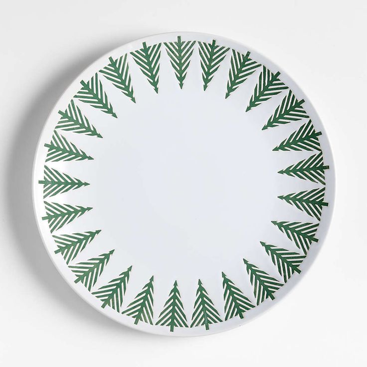 a green and white plate with pine branches on the rim, against a white background