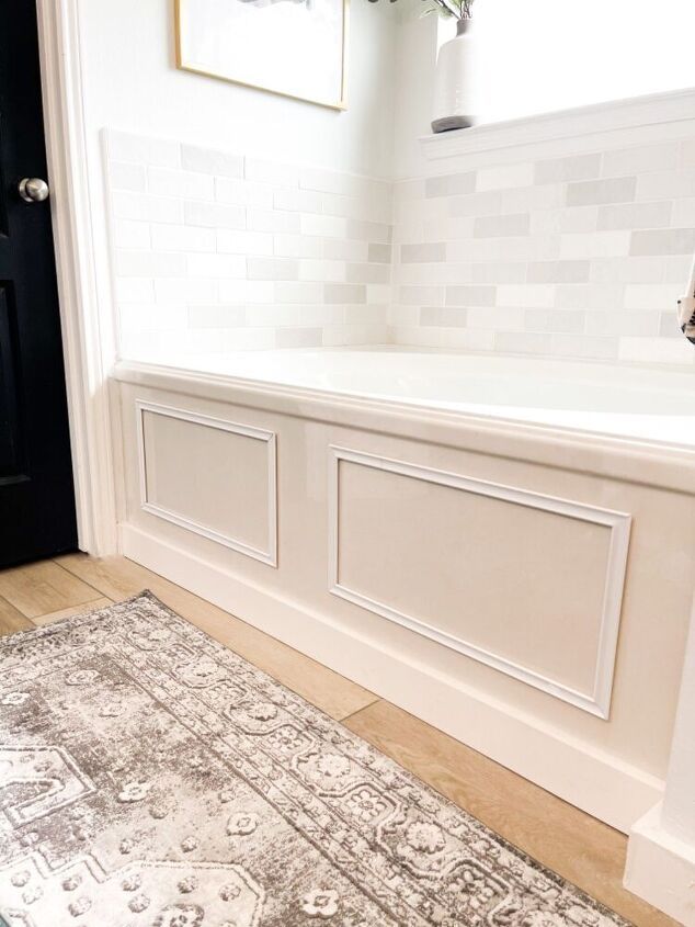 a rug is on the floor in front of a black door and white tile wall