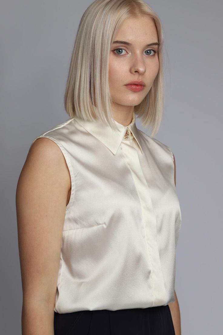 This sleeveless satin blouse with a concealed button placket and pointed collar is the perfect wardrobe staple for creating stylish looks. Crafted from high-quality 100% natural satin silk, it exudes elegance and modernity, adding a touch of luxury to any outfit. Its minimalist cut beautifully highlights femininity, while the smooth texture of the fabric gently drapes over the figure. The decorative placket not only serves a practical purpose but also adds a refined touch to the garment. The pointed collar brings sophistication, making this blouse suitable for both office attire and evening events. Available in a wide array of colors, you can choose the perfect shade that reflects your individuality and style. It pairs effortlessly with skirts, trousers, or blazers, allowing for the creati Chic Party Blouse With Spread Collar, Elegant Satin Top With Spread Collar, Chic Evening Blouse With Spread Collar, Chic Spread Collar Blouse For Evening, Elegant Sleeveless Semi-formal Tops, Chic Summer Blouse With Fold Down Collar, Chic Fold Down Collar Summer Blouse, Chic Fold Down Collar Blouse For Summer, Elegant Silk Tops With Lapel Collar