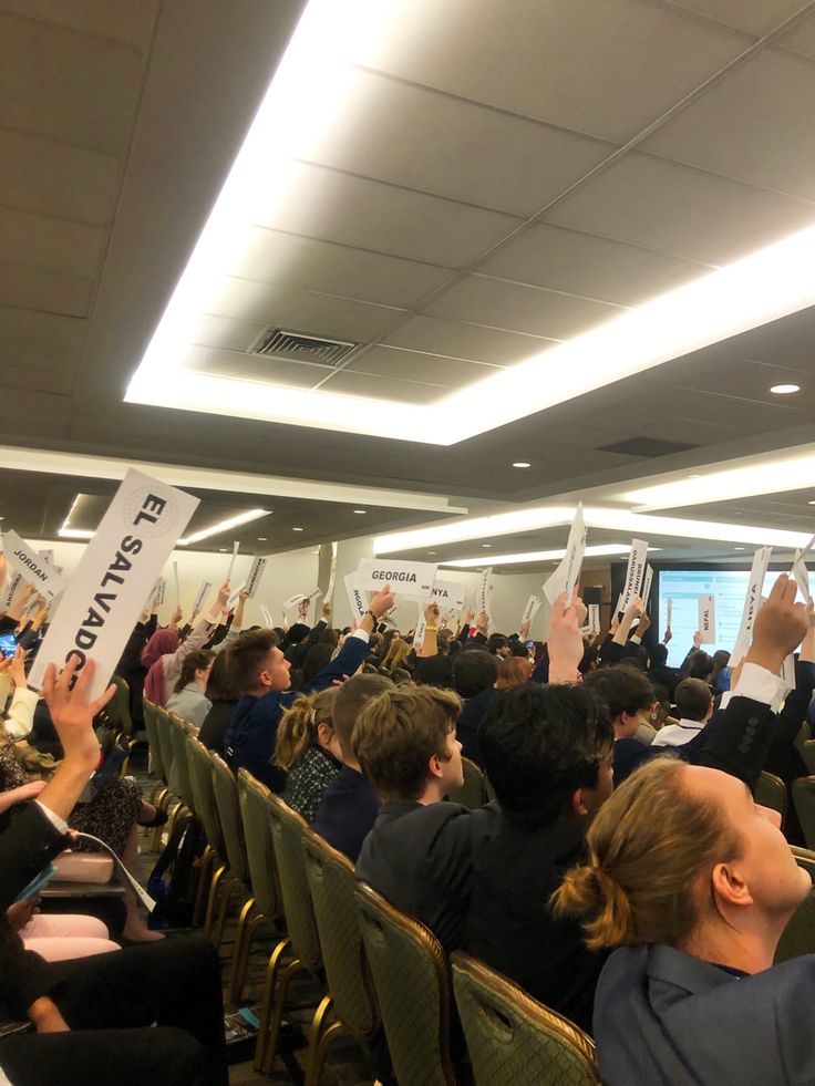 a group of people sitting in chairs holding up signs and raising their hands to the sky