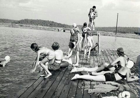 some people are sitting on a dock by the water