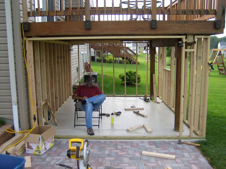 a man sitting in a chair on top of a patio next to a house under construction