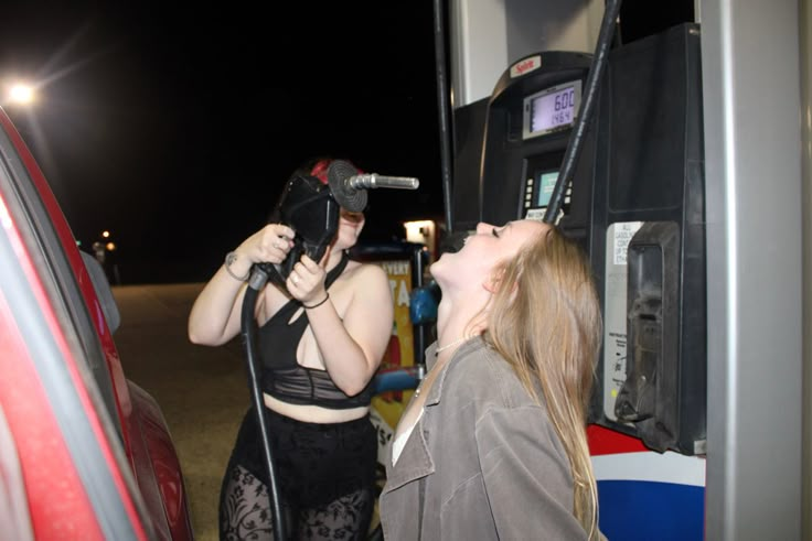 two women standing next to each other in front of a vending machine at night