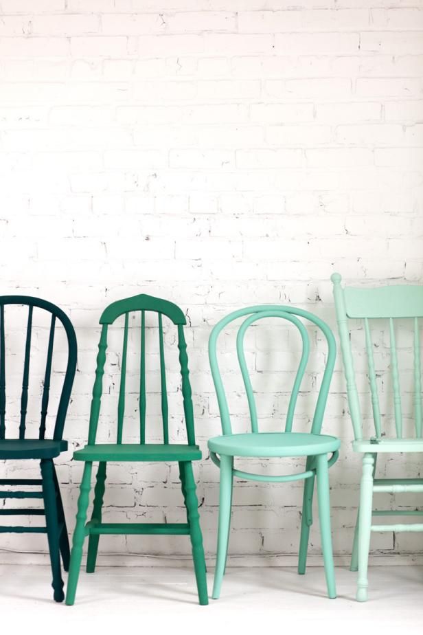 three chairs in different colors against a white brick wall, one is green and the other is blue