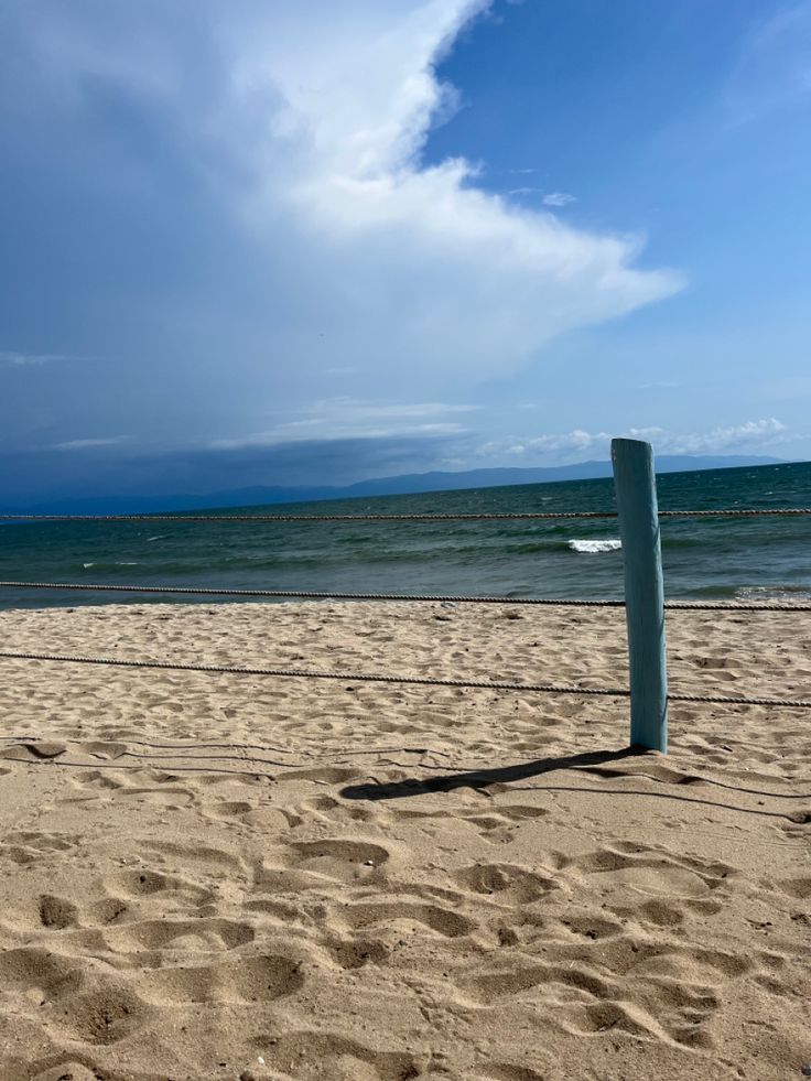 a blue pole on the beach with waves in the background