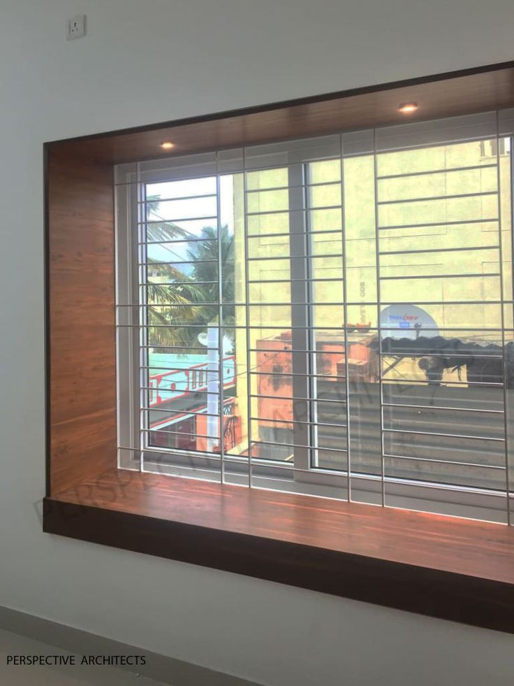 a window with wooden slats and blinds on the outside, in front of a white wall