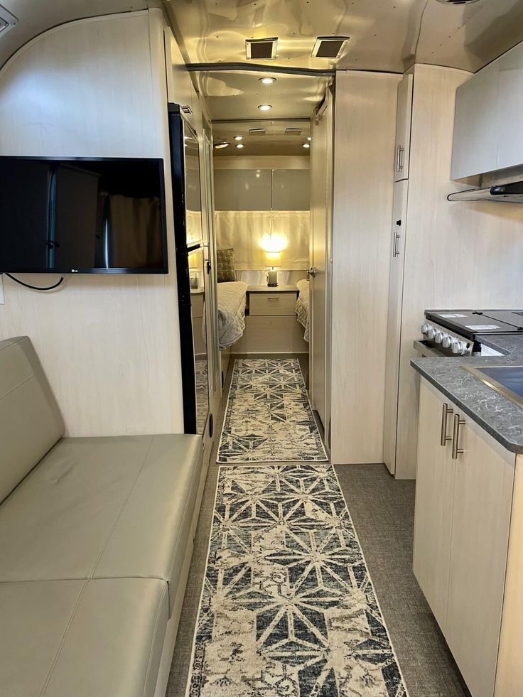 the interior of an rv with a couch and television on the wall next to it