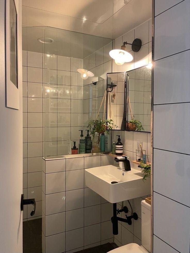 a bathroom with a toilet, sink and mirror in it's corner area next to a wall mounted faucet