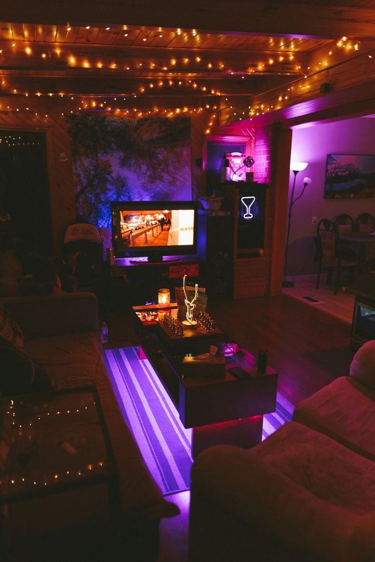 a living room filled with furniture and purple lights on the ceiling above it is a flat screen tv