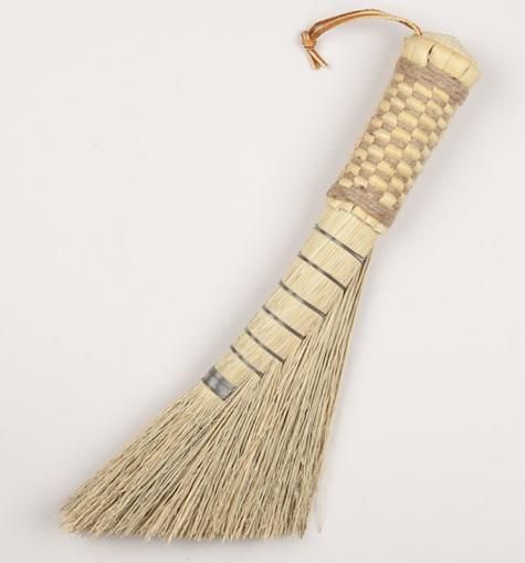 a long tassel hanging from a hook on a white surface with a wooden handle