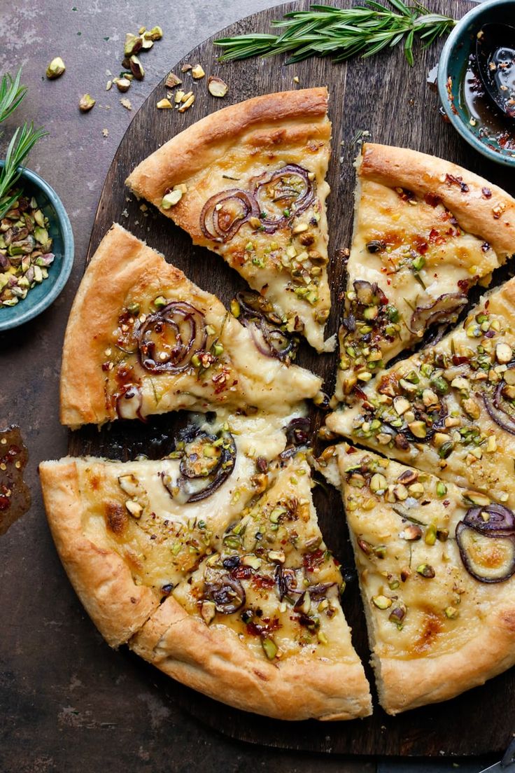 a pizza cut into eight slices on top of a wooden cutting board with olives