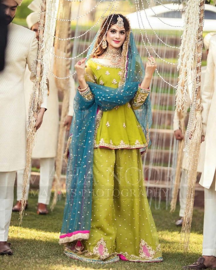 a woman in a green and blue outfit standing next to other people wearing white outfits