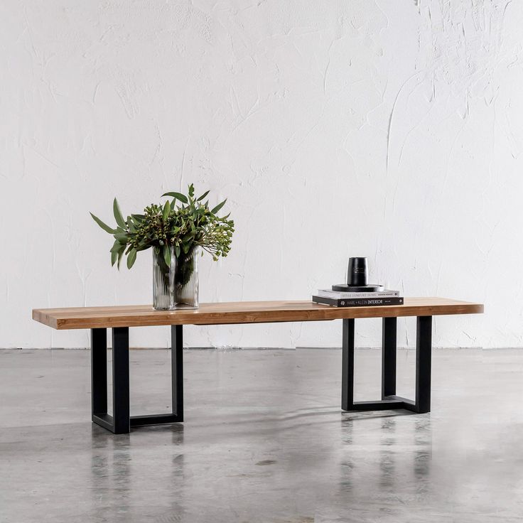 a wooden table with black metal legs and a potted plant sitting on top of it