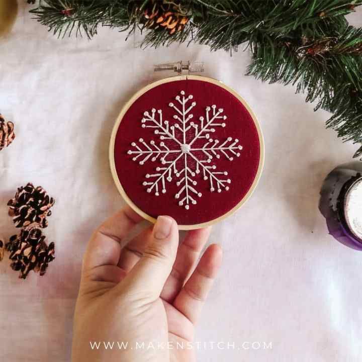 someone is stitching a snowflake ornament on a piece of fabric