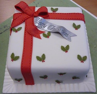 a white cake decorated with holly and red ribbon