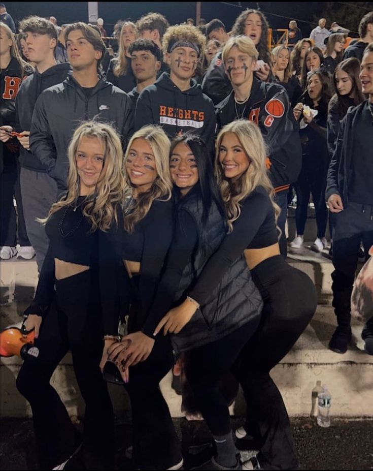 a group of young people standing next to each other in front of a crowd at night