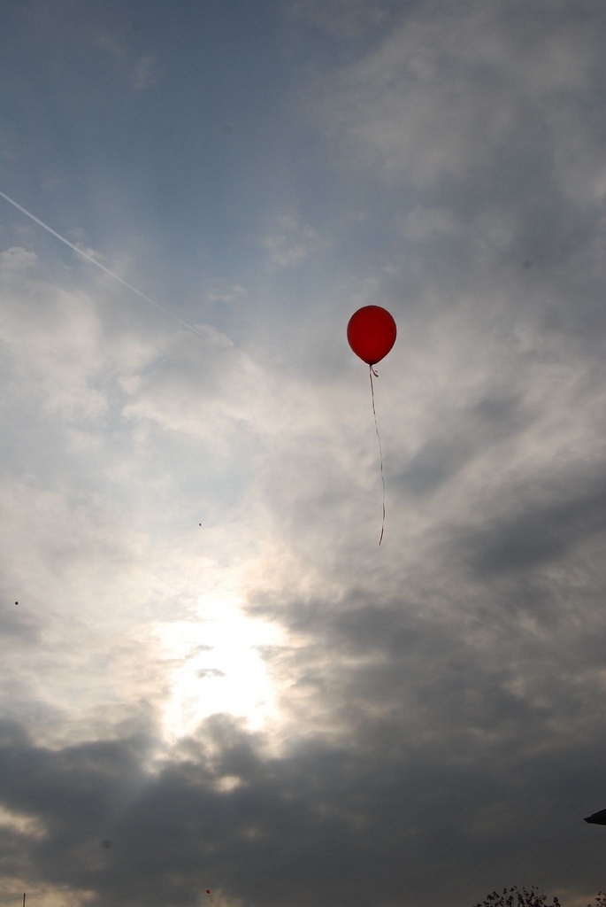 a red balloon is flying in the sky