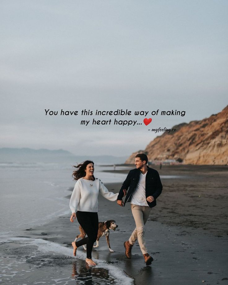 a man and woman walking on the beach holding hands with a dog in front of them