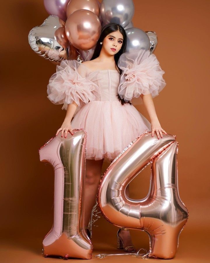 a woman in a pink dress is holding balloons and the number four balloon letters are all around her