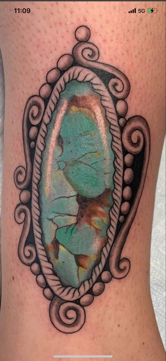 a woman's thigh with a mirror tattoo on the side of her leg, and an image of a fish in it