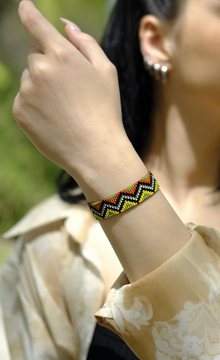 a woman is wearing a colorful bracelet on her wrist and looking up at the sky