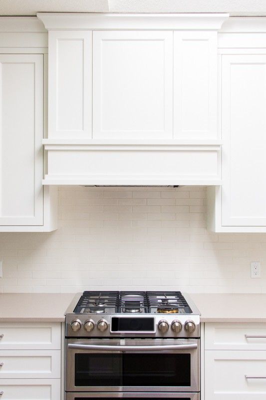 a stove top oven sitting inside of a kitchen next to white cupboards and drawers