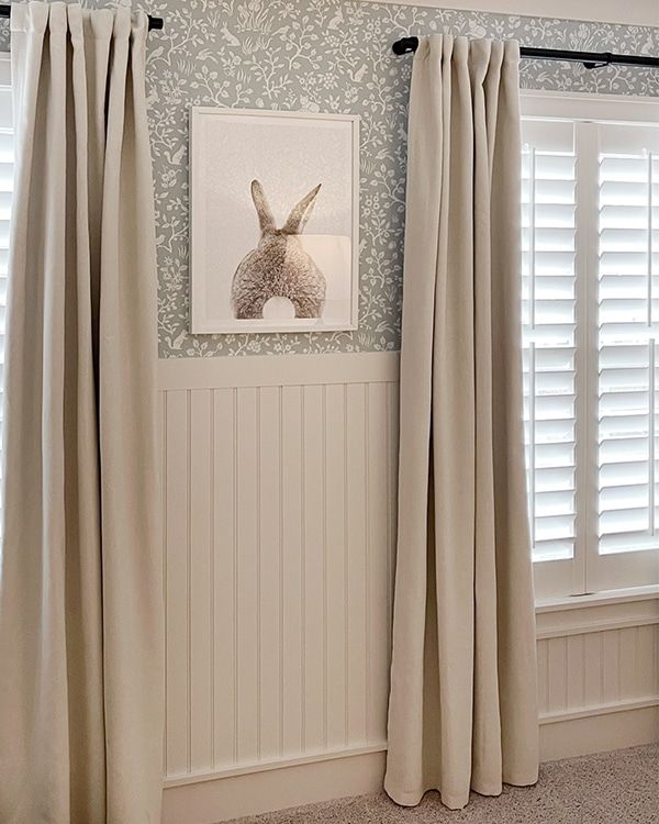 the curtains are pulled back in front of the window with white shutters on both sides