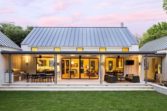 an open concept house with glass walls and sliding doors on the front door is shown at dusk