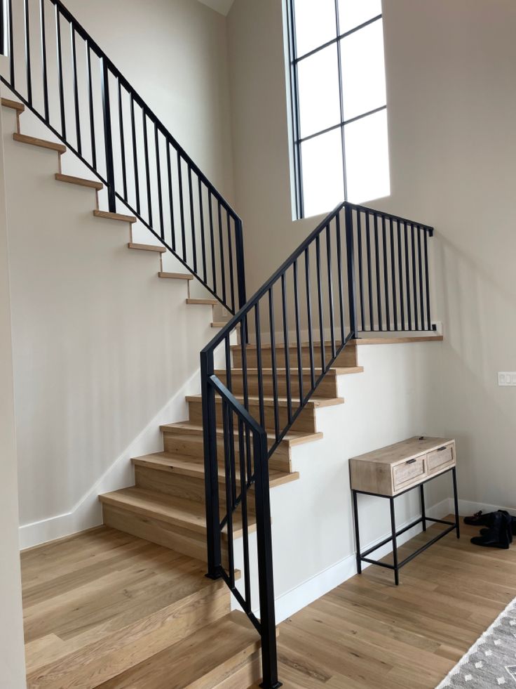 there is a stair case next to the bed in this room with white walls and wooden floors