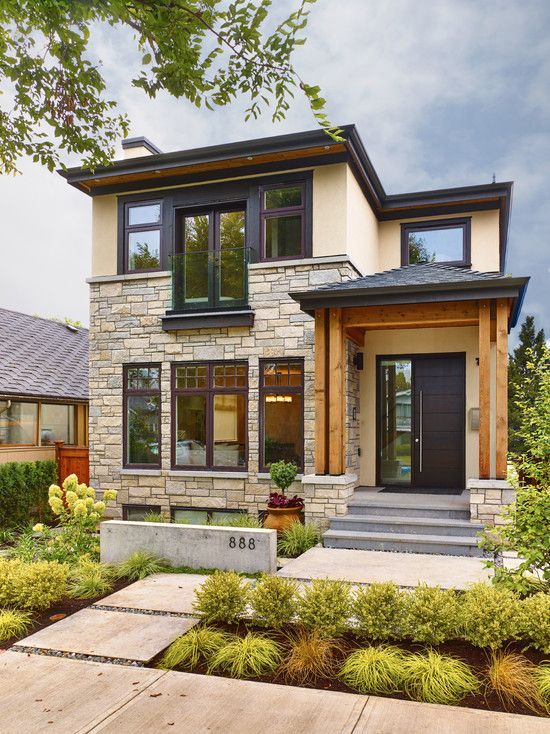 a modern house with stone and wood accents in the front yard, surrounded by landscaping