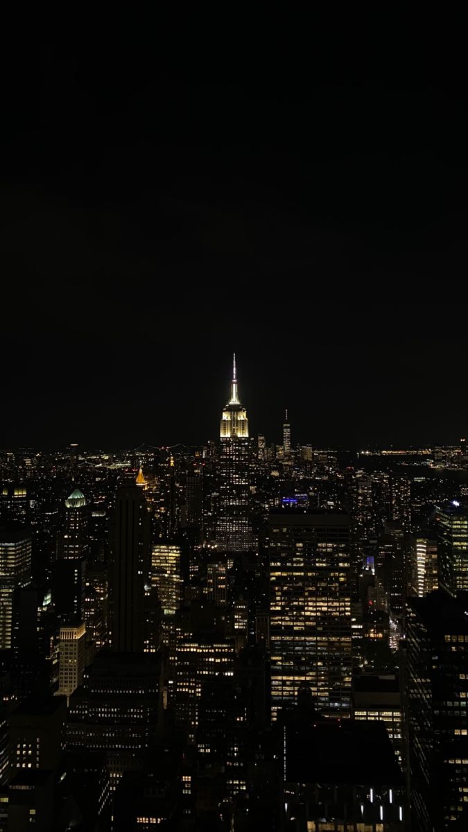 the empire building is lit up at night in new york's cityscape