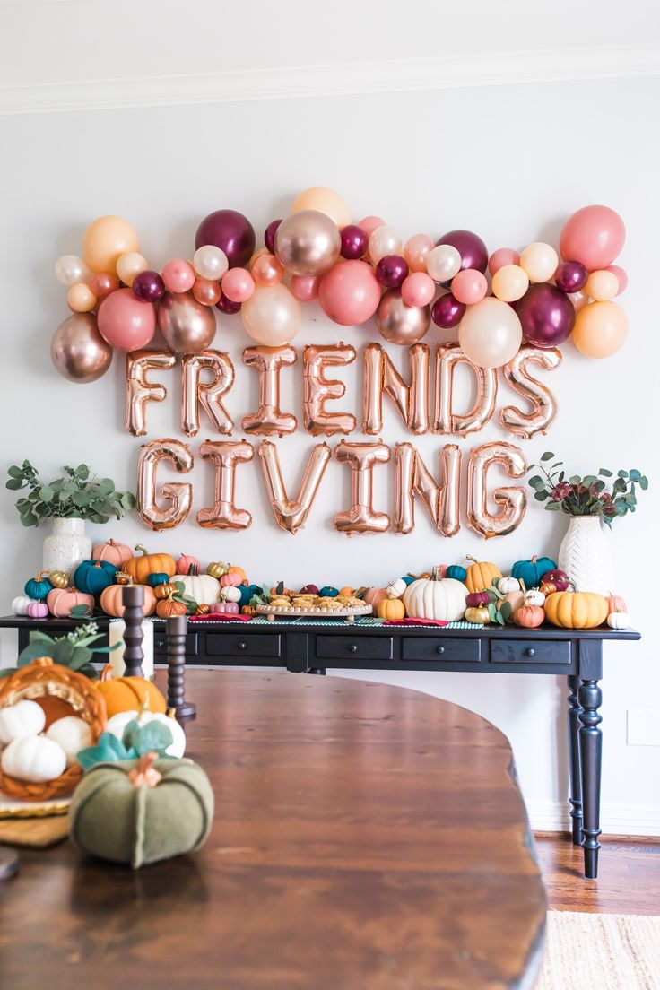 a dining room table with balloons and pumpkins on it, along with a sign that says friends giving