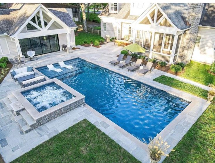 an aerial view of a backyard with a swimming pool and hot tub in the middle