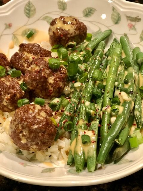 a white plate topped with meatballs and green beans