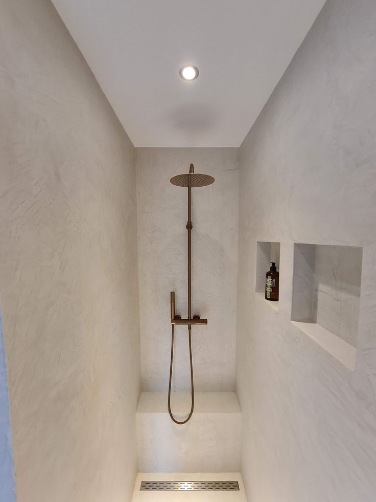 a bathroom with a walk in shower next to a white wall and tiled flooring