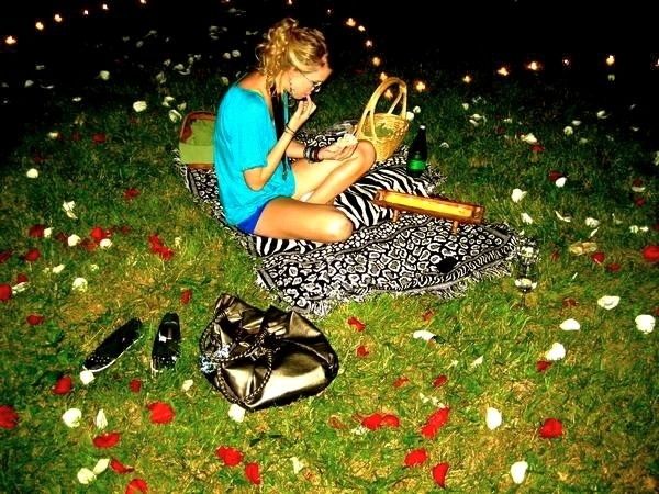 a woman sitting in the grass with her hand on an instrument and some shoes next to her