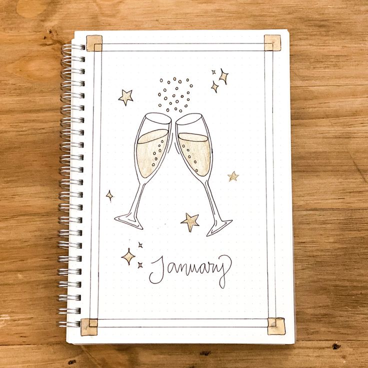 a spiral notebook with two glasses of champagne on it and the words january written in cursive writing