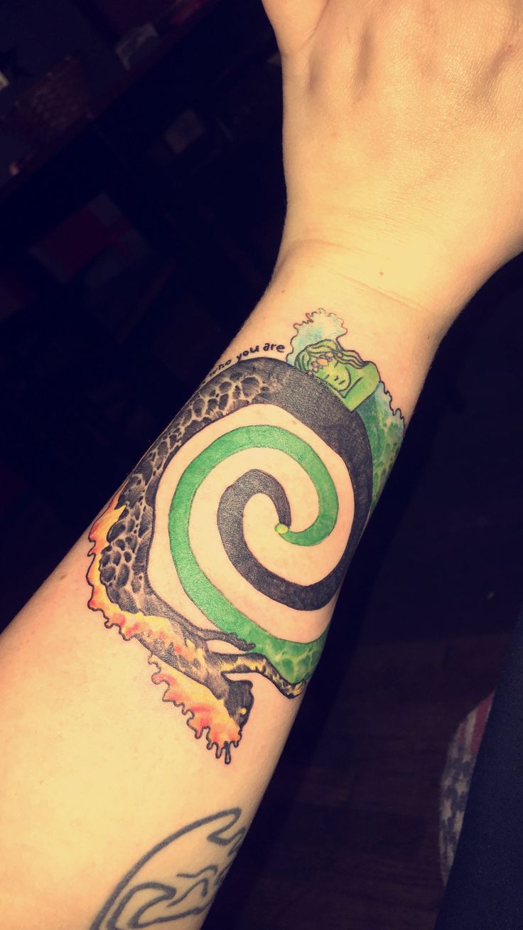 a person's arm with a green and black spiral tattoo on the left wrist