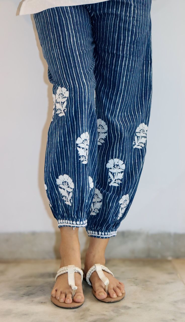 Elevate your style effortlessly with our Pure Cotton Block Printed Stripe Pant in a mesmerizing indigo hue. The perfect blend of tradition and contemporary flair, these pants feature eye-catching Chikankari embroidery in enchanting flower motifs. Crafted from pure cotton, these pants provide a luxurious feel against your skin, ensuring comfort all day long. The indigo hue adds a touch of sophistication, while the block-printed stripes infuse a modern edge, creating a harmonious fusion of timeless elegance and current trends. The highlight of these pants lies in the exquisite Chikankari embroidery that graces them. Delicate flower motifs add a charming and feminine touch, making these pants a standout piece in your wardrobe. Whether you're headed for a casual outing or a special occasion, t Indigo Cotton Pants For Summer, Summer Cotton Pants In Indigo, Spring Cotton Indigo Pants, Bohemian Chikankari Embroidery Bottoms For Summer, Traditional Cotton Straight Leg Bottoms, Festive Traditional Cotton Pants, Traditional Straight Leg Cotton Bottoms, Traditional Festive Cotton Pants, Festive Blue Cotton Pants