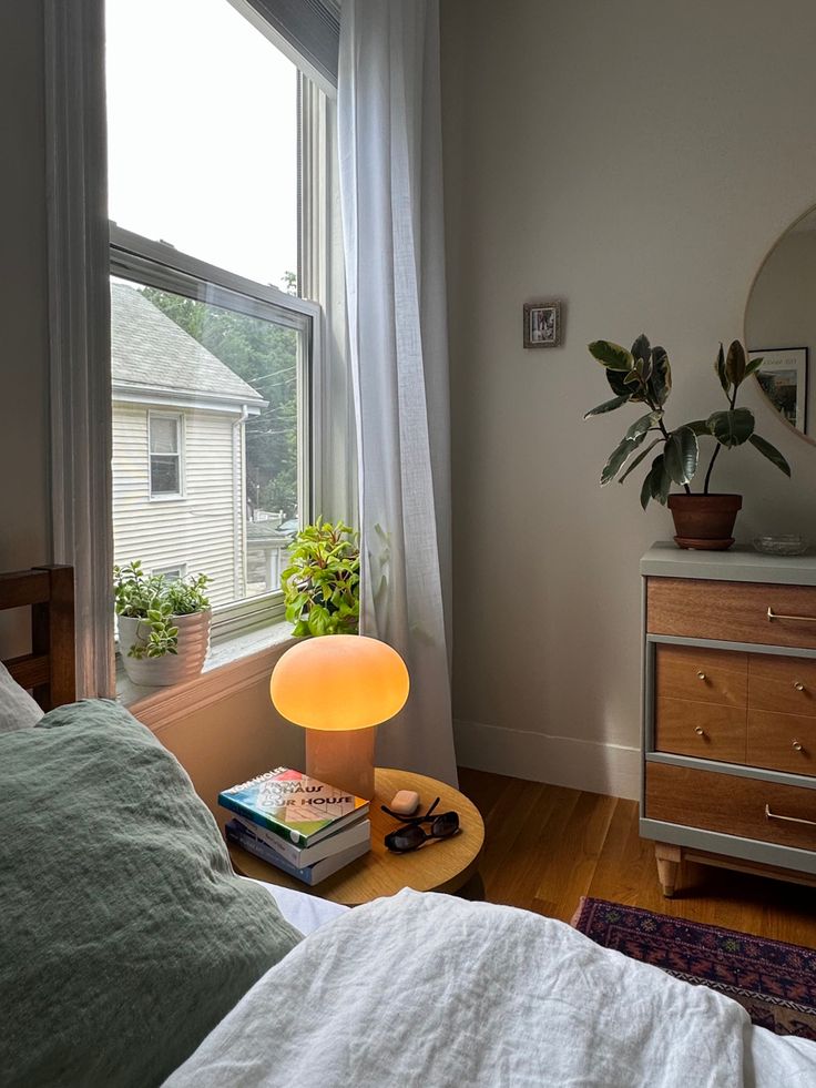 a bedroom with a bed, dresser and mirror in it next to a large window