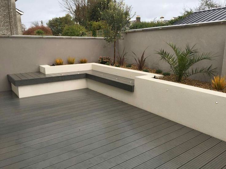 a wooden deck with benches and plants on it