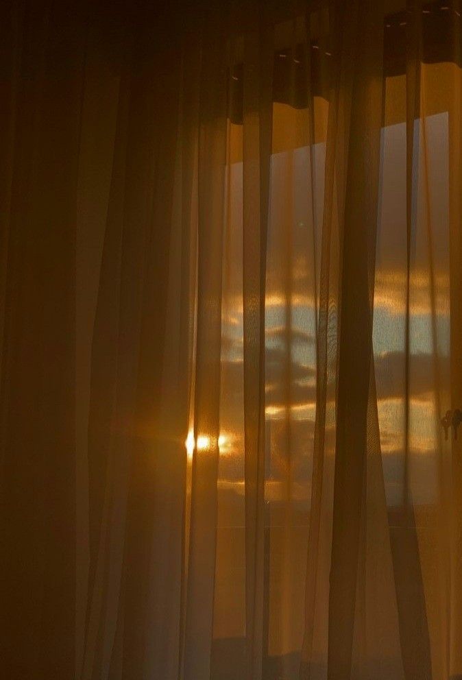 the sun is shining through sheer curtains